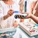 Woman tapping a credit card on a wireless payment terminal at a boutique store.