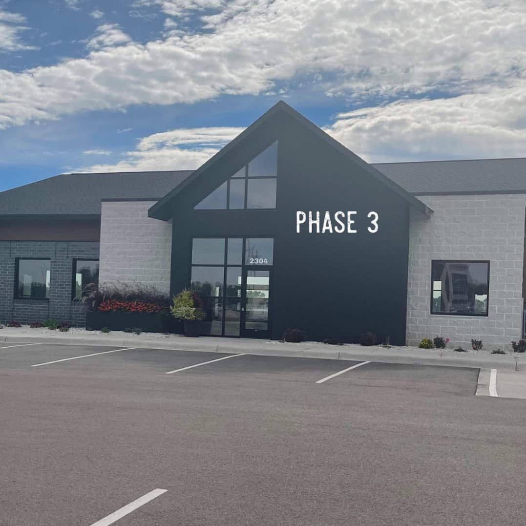 Visit Phase 3 Payments—transparent, local, and service-first solutions. Modern office building with “Phase 3” displayed on the front, under a partly cloudy sky.