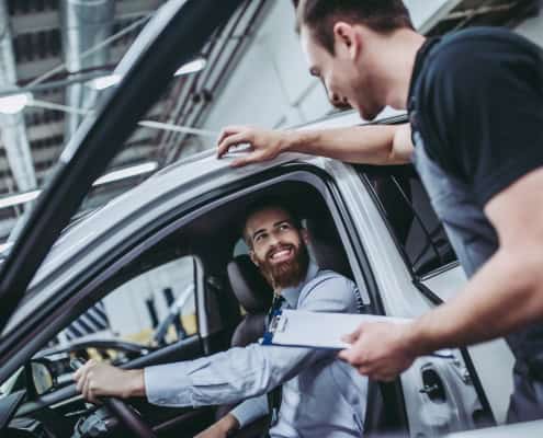 Smiling mechanic talking to a customer in a car repair shop.