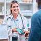 Secure and seamless payment solutions for healthcare and wellness. - Phase 3 Payments Smiling pharmacist accepting a contactless payment from a customer at a pharmacy counter.